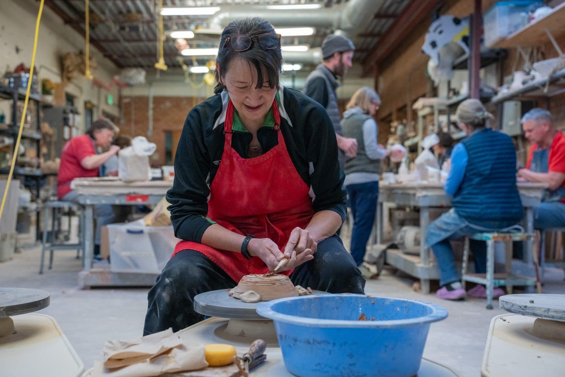 Woman shaping clay in pottery workshop class